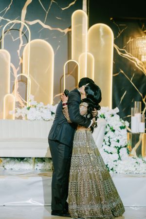 Couple sharing intimate dance moment at wedding reception with illuminated white backdrop.