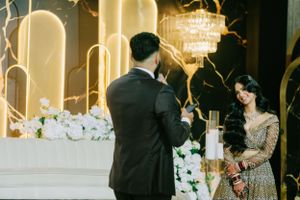 A couple shares their first dance at an elegant wedding reception with glowing arches and floral decorations.
