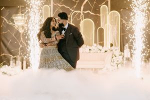 Couple dancing surrounded by indoor sparklers and dramatic lighting effects at an elegant reception.