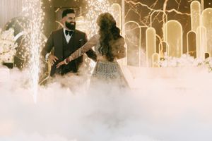 A couple shares a romantic moment in a dreamy white misty setting with glowing lights in the background.