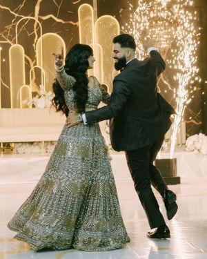 A joyful dancing moment between a couple in formal attire with cascading sparklers in the background.