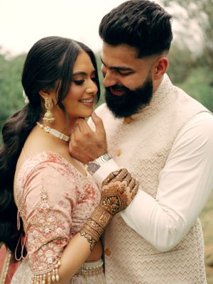 A tender moment between a couple wearing South Asian formal attire and traditional jewelry.