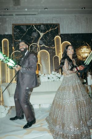 A couple dances joyfully in front of a golden backlit marble wall.