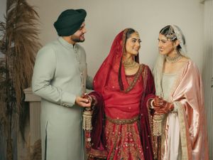 Traditional Sikh wedding ceremony with guests wearing formal ethnic attire in red, pink and light colors.