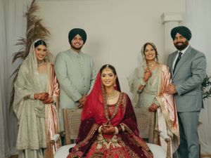 Traditional Punjabi wedding group portrait featuring a bride in red lehenga surrounded by family in elegant traditional attire.