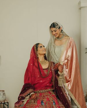 Two people wearing traditional Indian wedding attire share an intimate moment in soft lighting.