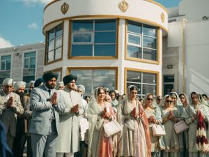 A group stands in prayer outside a modern curved building with golden architectural accents.