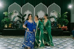 Traditional dancers perform at an elegant wedding reception with ornate white lattice backdrop and blue and green outfits.