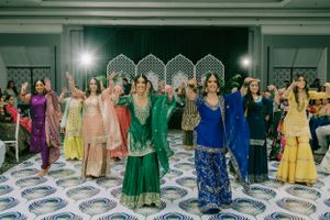 Colorfully dressed guests dance together on a patterned floor during a festive celebration event.