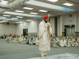 Traditional Sikh wedding ceremony in a large hall with guests seated on the floor.