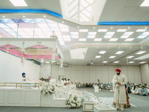 A modern indoor event space decorated with white floral arrangements and pink decor elements under bright ceiling lights.