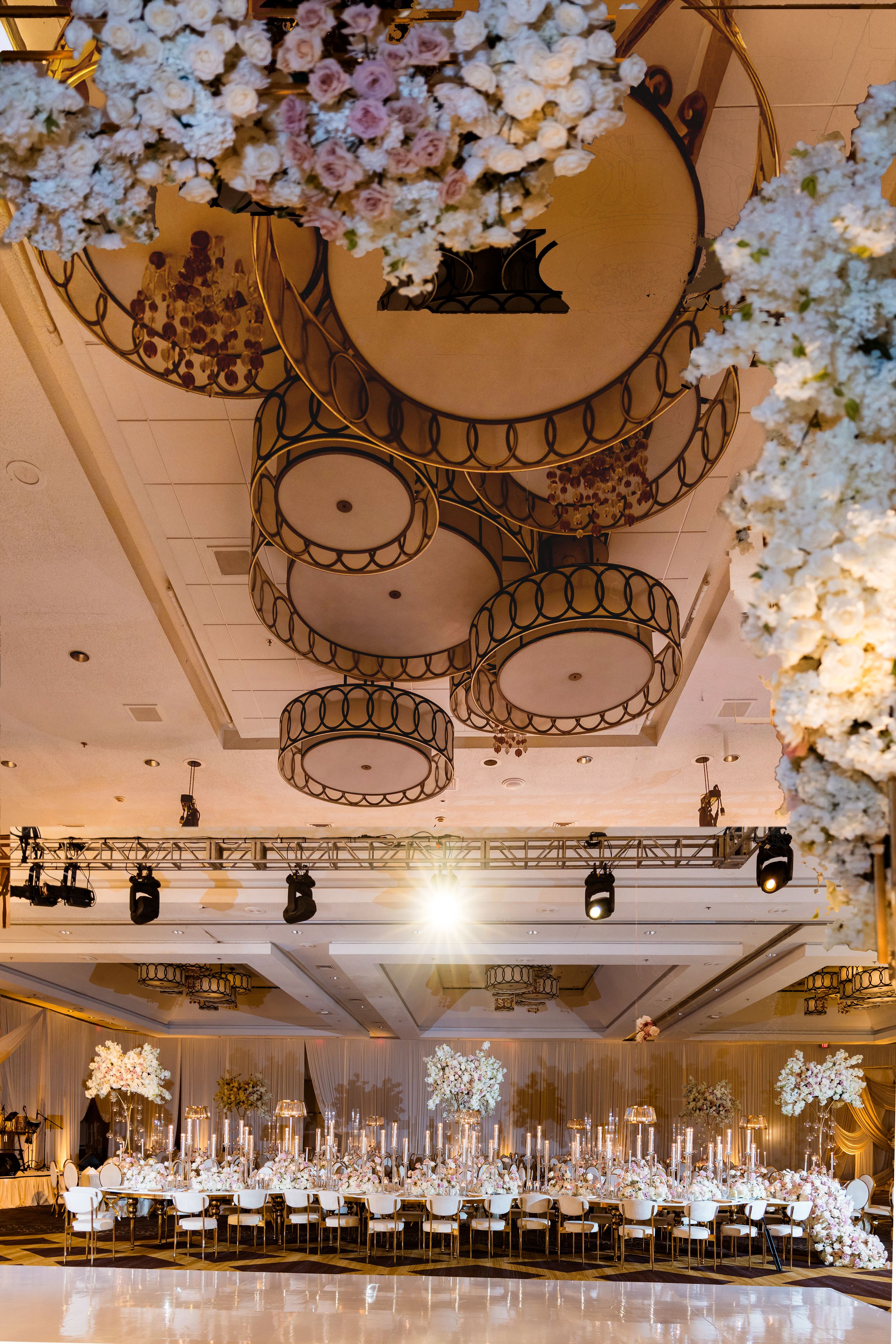 Elegant ballroom with white floral decor and ornate chandeliers arranged in a panoramic sequence of interior shots.