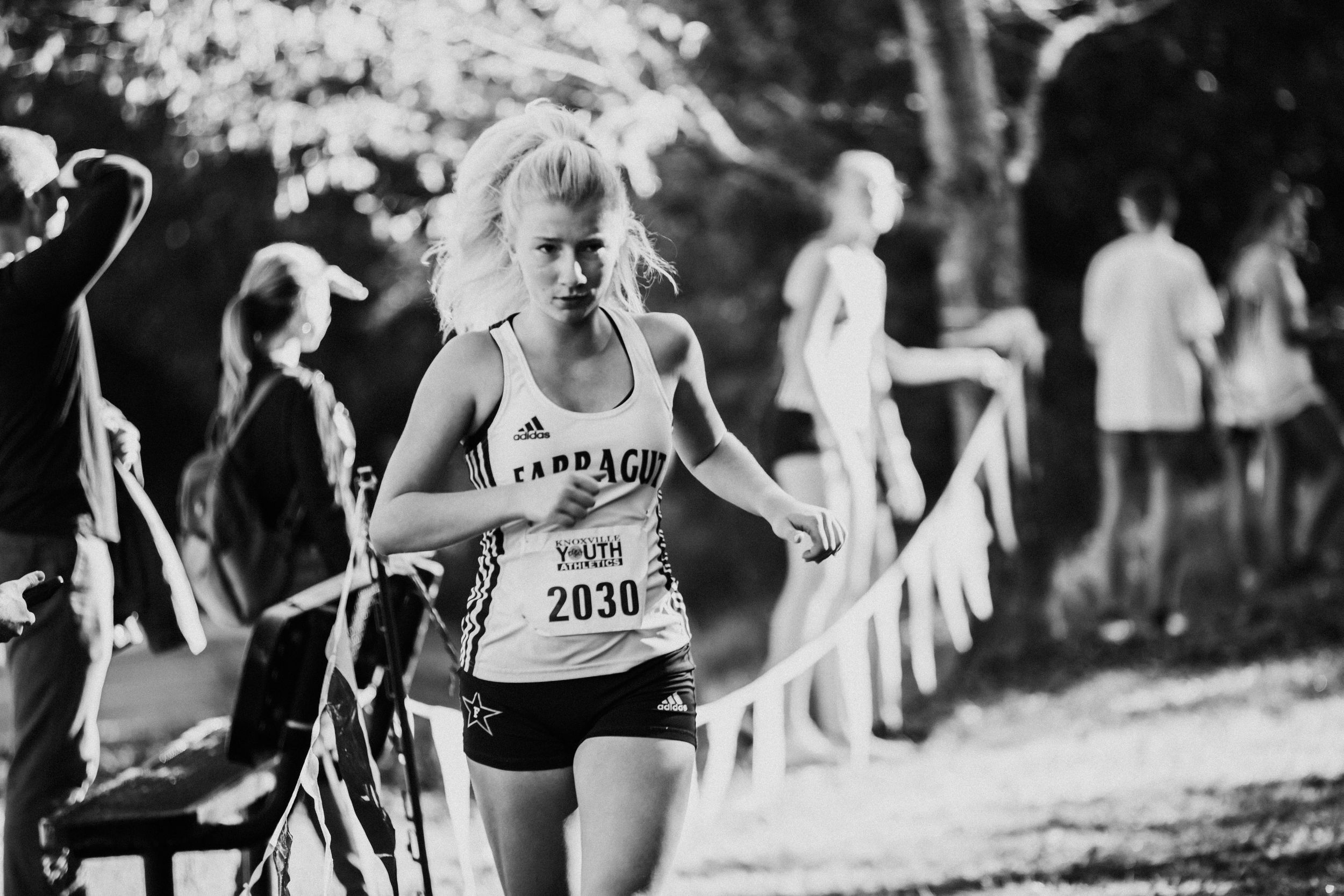 Runner competes on wooded cross country course during fall race event.