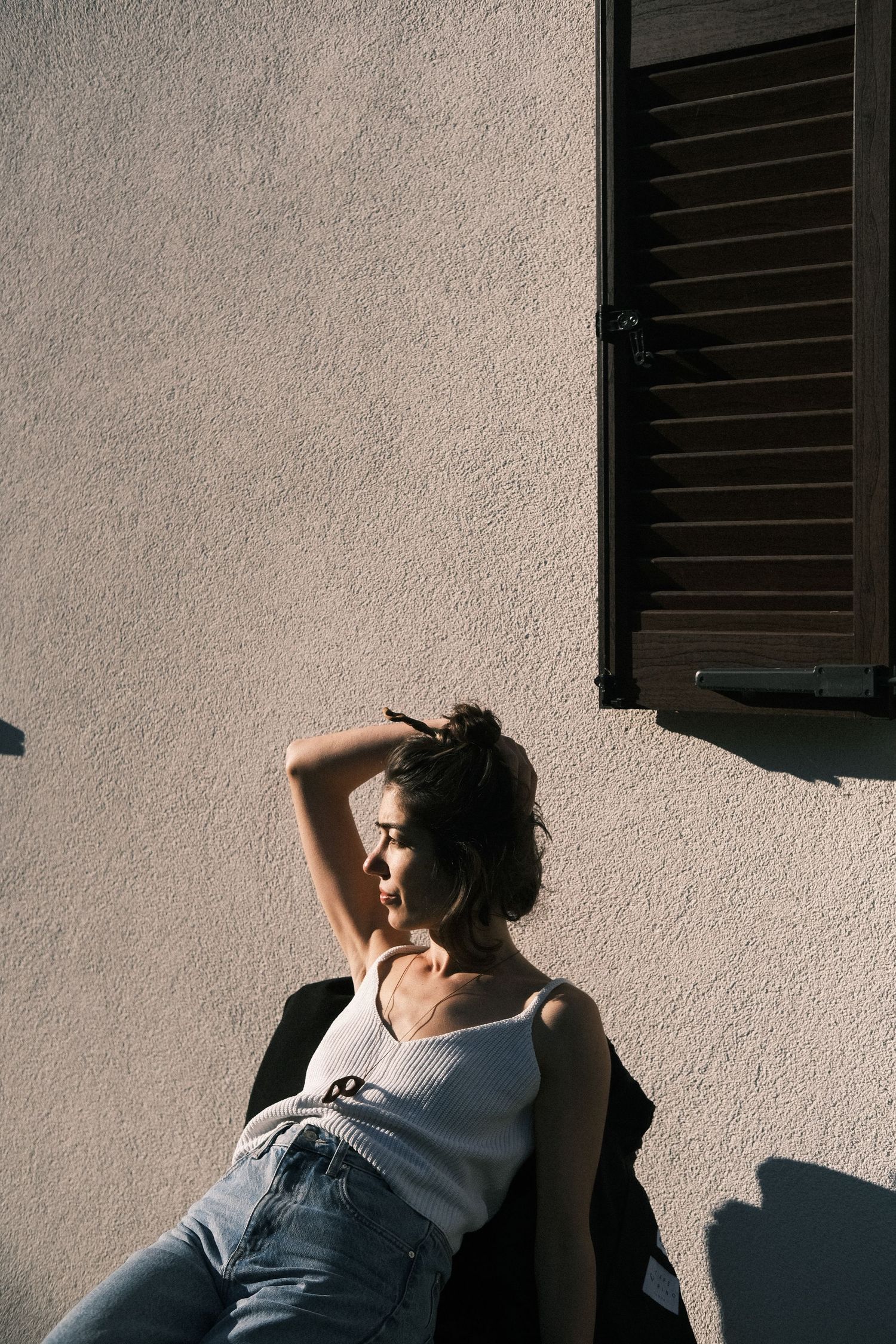 Dramatic shadows cast on white wall with figure in natural lighting.