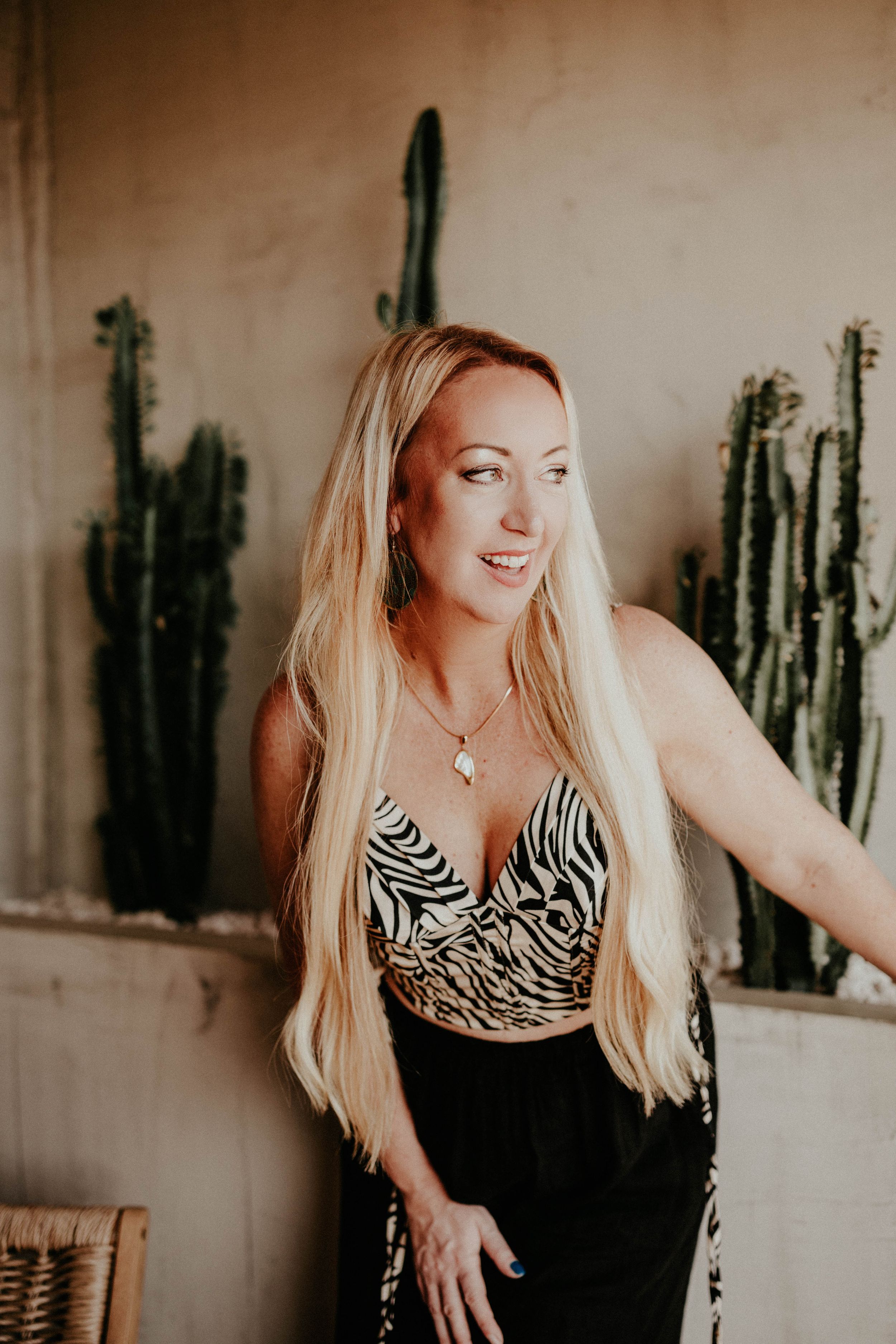 A woman in a zebra print top poses against a wall with cacti decor in a series of candid shots.