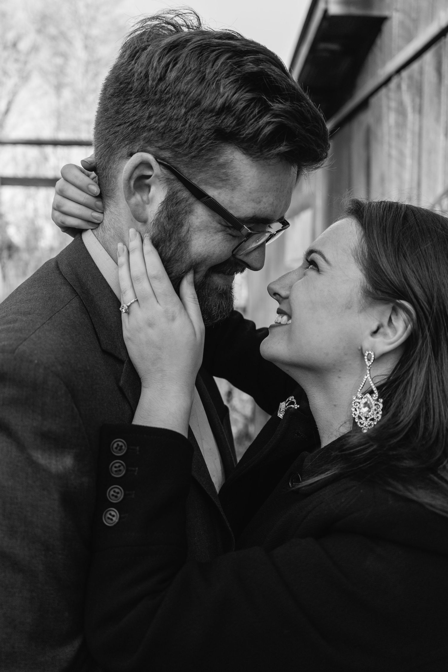 A romantic black and white portrait of a couple sharing an intimate moment, with the woman gently touching his face.