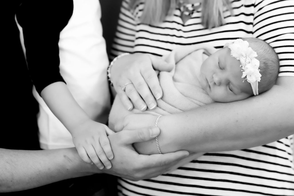 Black and white photo of newborn baby cradled in supporting hands.