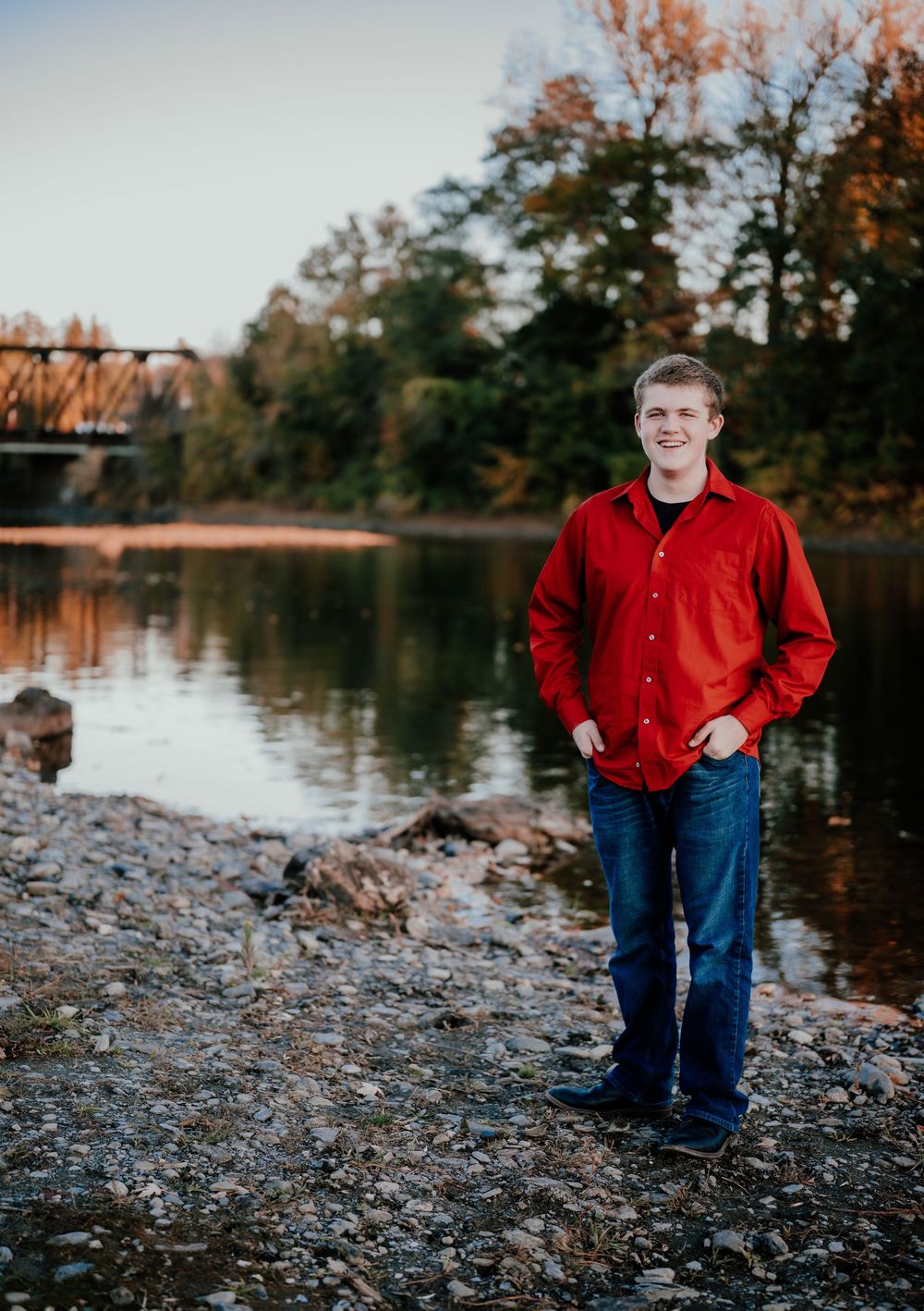 A series of four outdoor portraits taken at sunset by a rocky riverbank with fall foliage in the background.