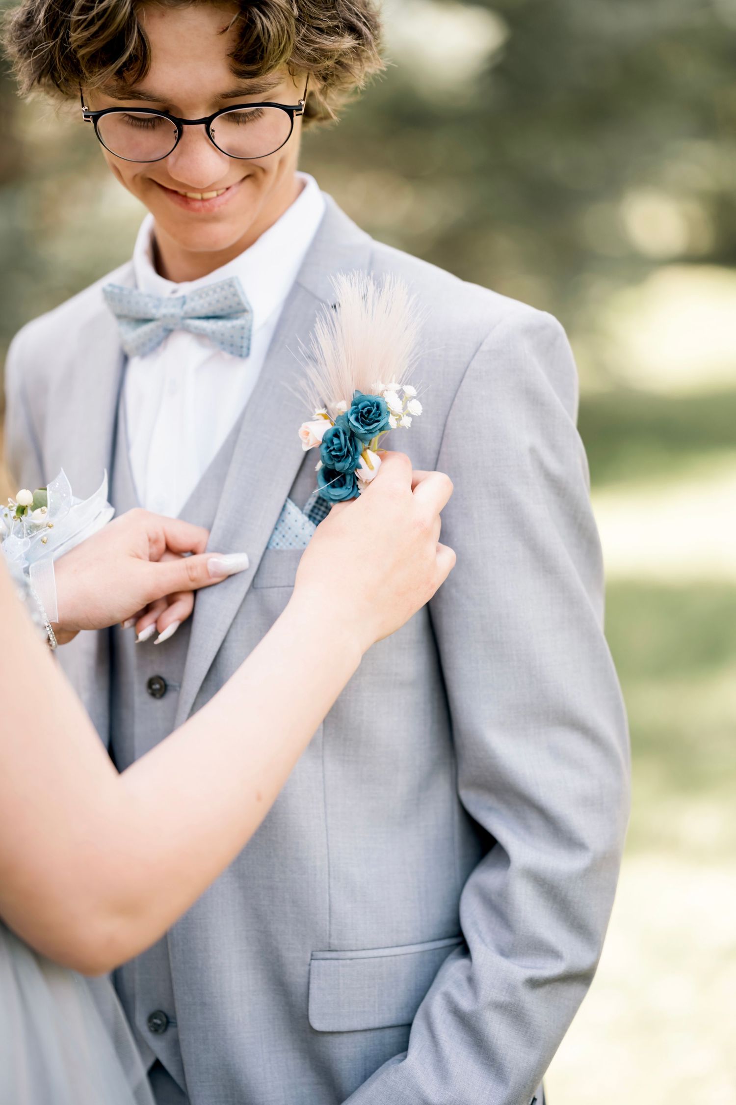 Close-up of someone in light gray suit having blue boutonniere pinned to lapel.