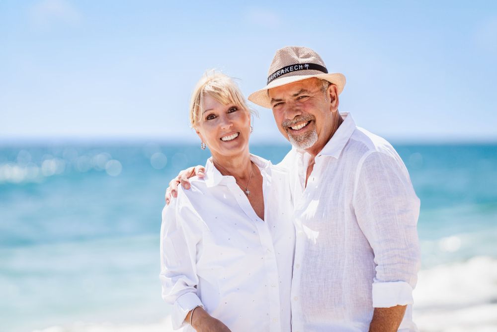 Loving couple embraces on beach wearing coordinated white outfits.