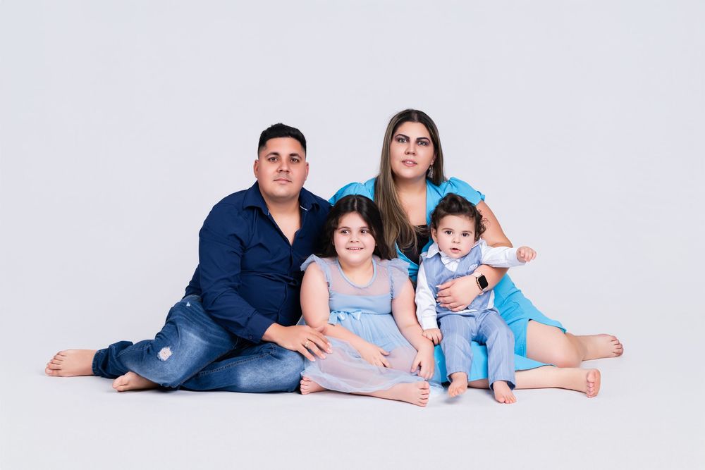 Family in coordinating blue outfits lounging together on white background.