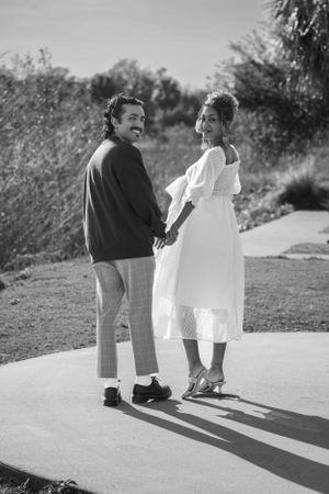 Black and white photo of couple walking together casting long shadows on path.