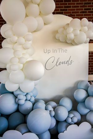 Elegant balloon installation featuring white and blue ombre effect with 'Up in the Clouds' text.