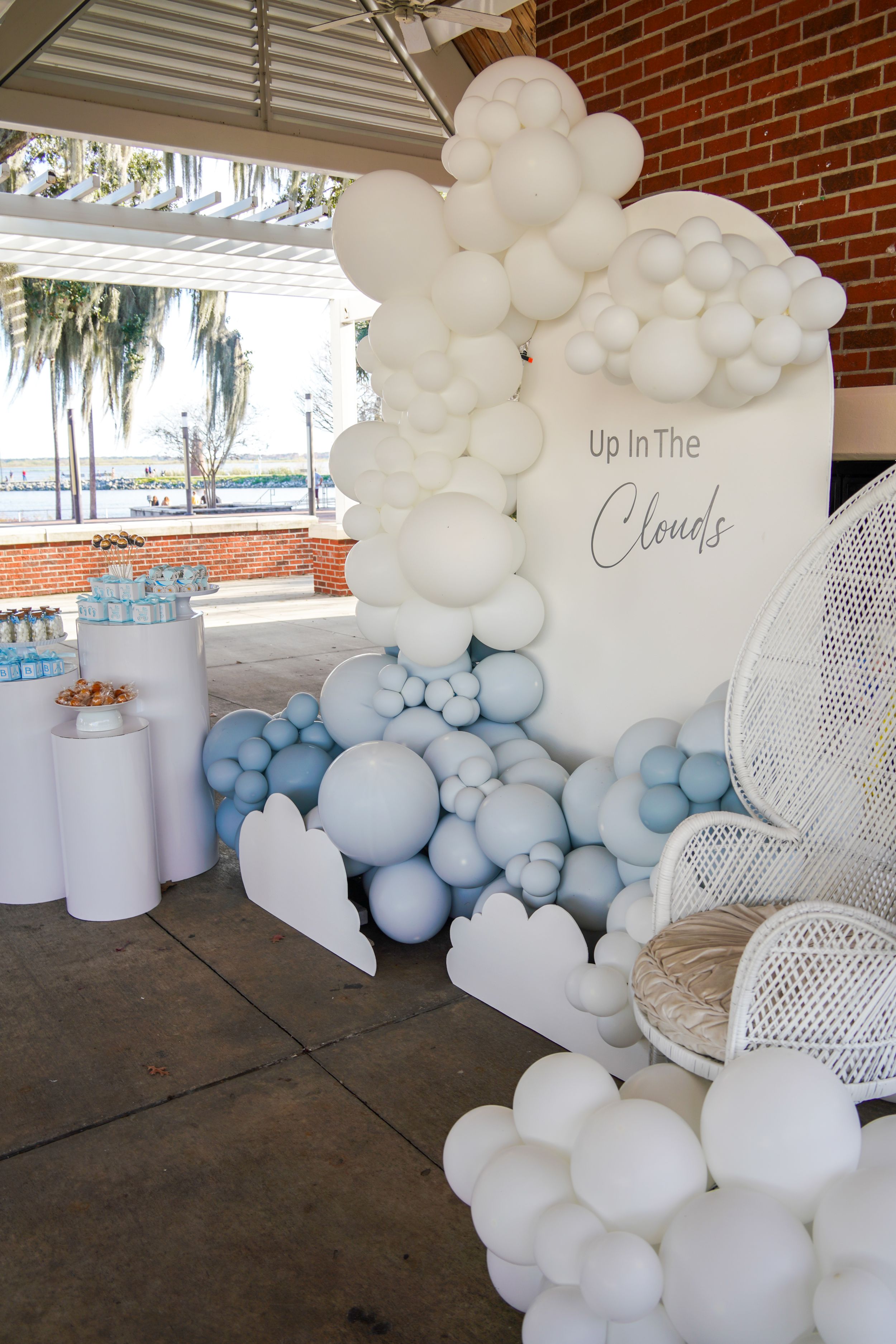 White and blue balloon arch installation with 'Up in the Clouds' text creates dreamy party backdrop.