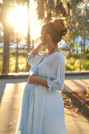 Maternity photoshoot at sunset with beautiful golden light filtering through trees.