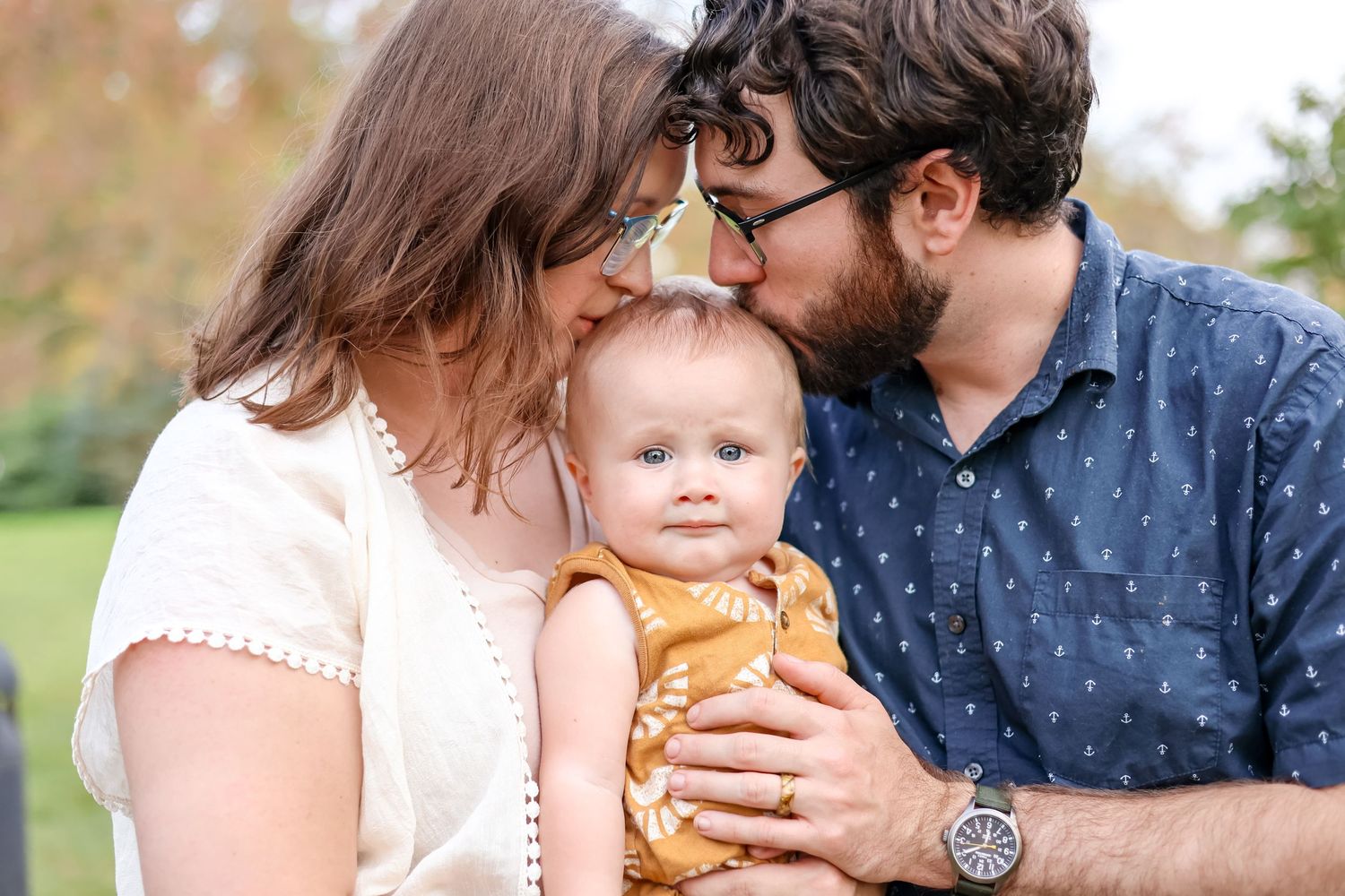 Springfield, IL Family photographer captures parents kissing their toddler's head during a family session in Central, IL