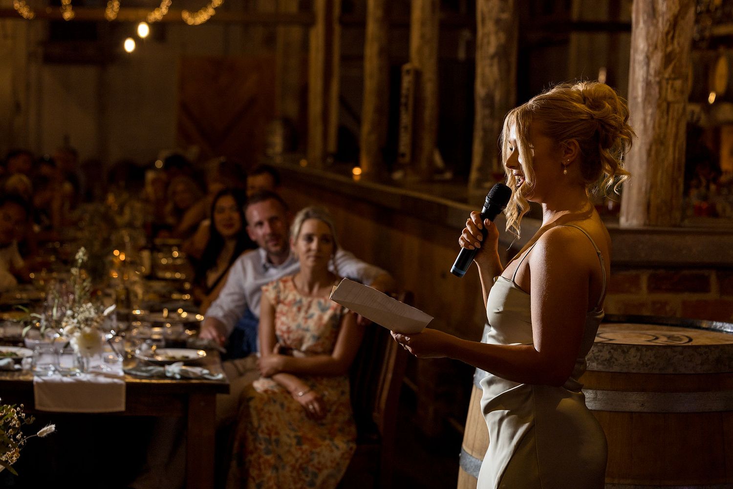 Maid of Honour deliver her speech at an elegant indoor venue with dramatic lighting and stone columns at the Corowa Distilling Company.