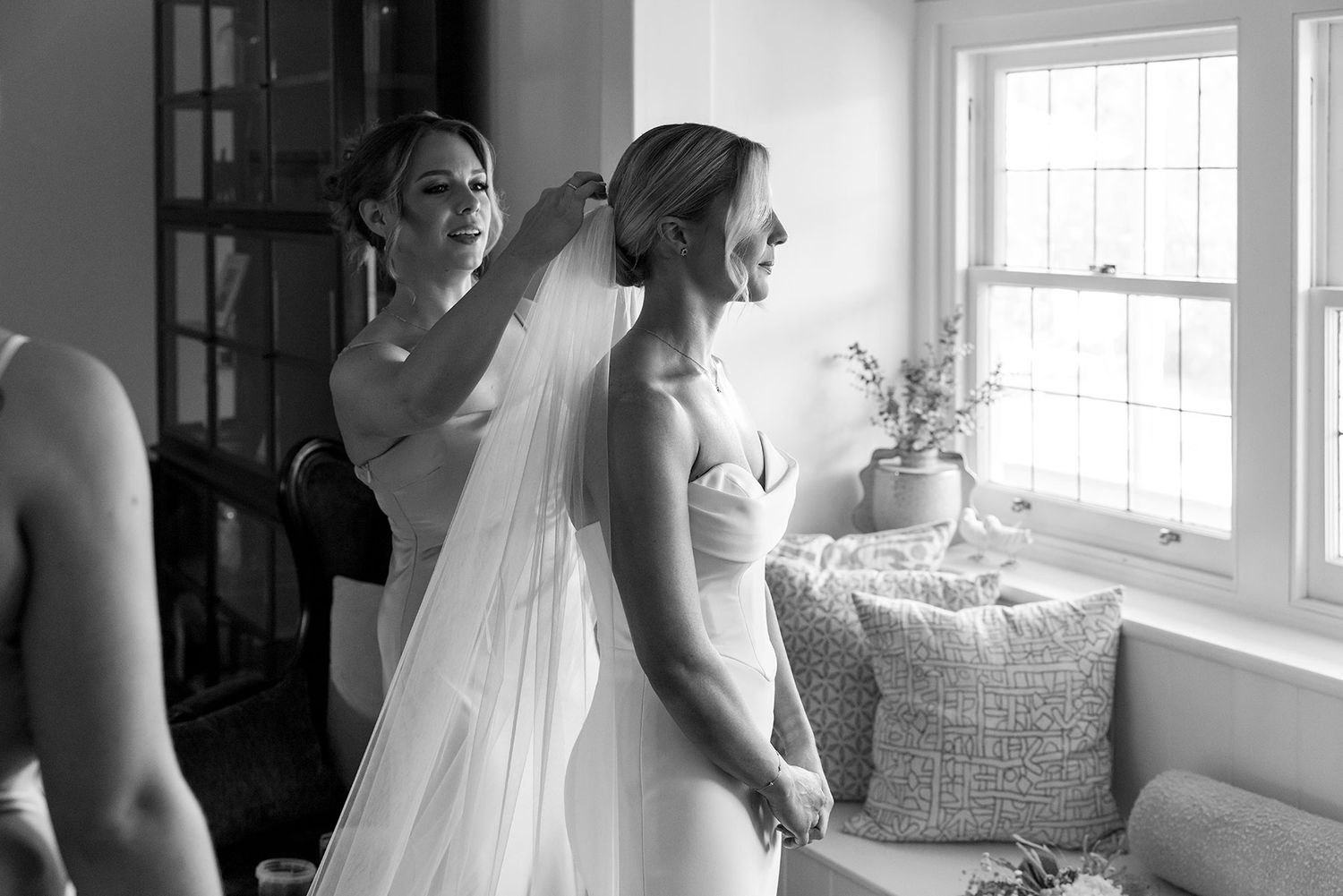 Bridesmaids help the Bride prepare for her wedding ceremony in a sun-lit room as they help with final dress adjustments at Quandong.