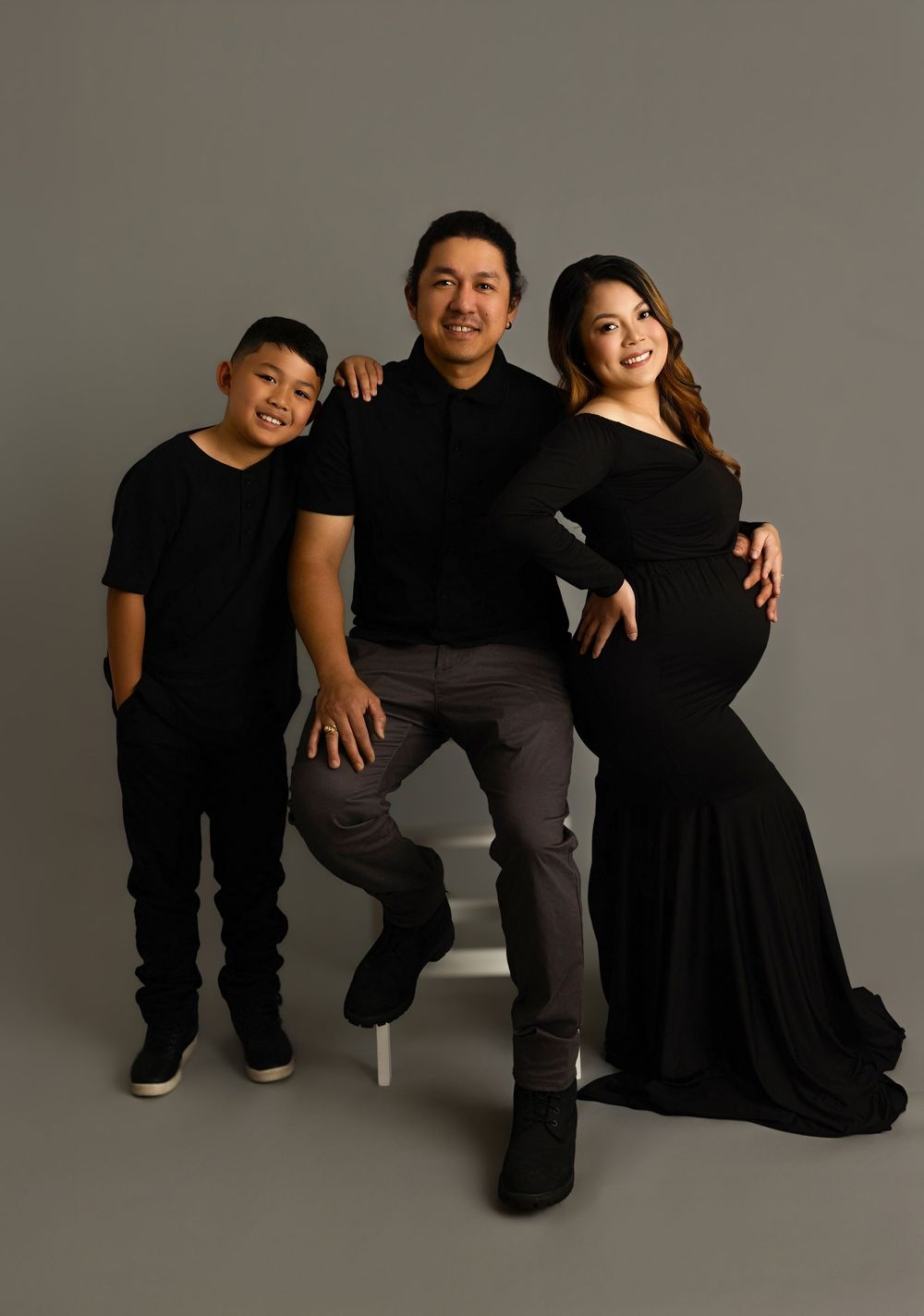 A playful series of studio photos showing three people in black and gray casual wear posing on a white stool.