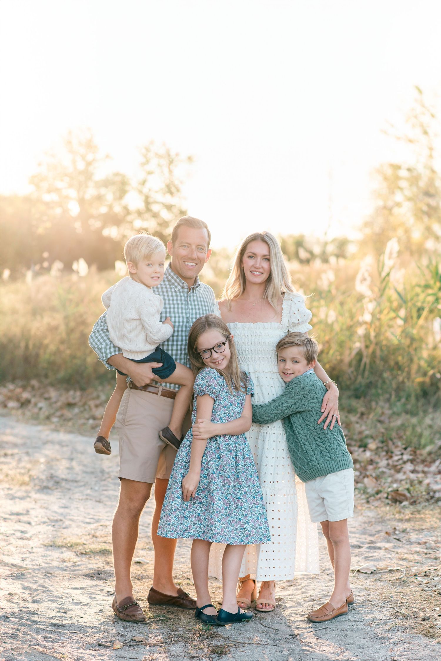 Warm family portrait on Manasquan Beach, New Jersey, surrounded by soft dunes and dressed in earth-toned outfits for a fall photo session.