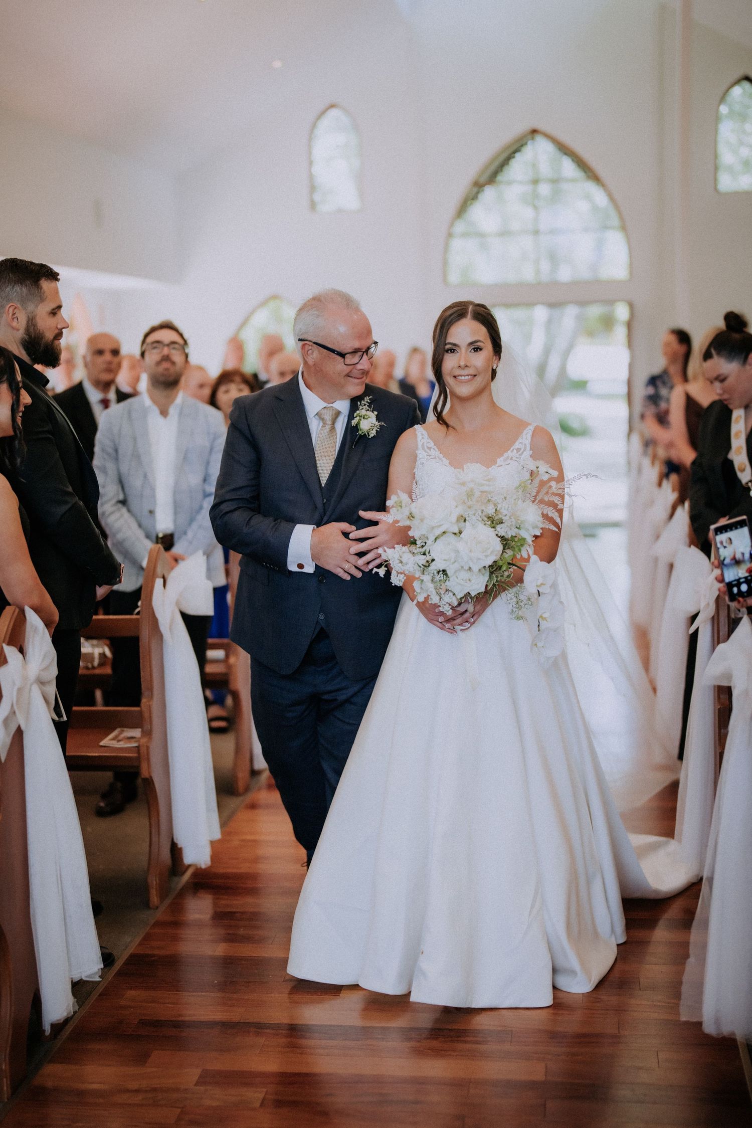 Traditional church wedding ceremony with white floral decorations and pews.