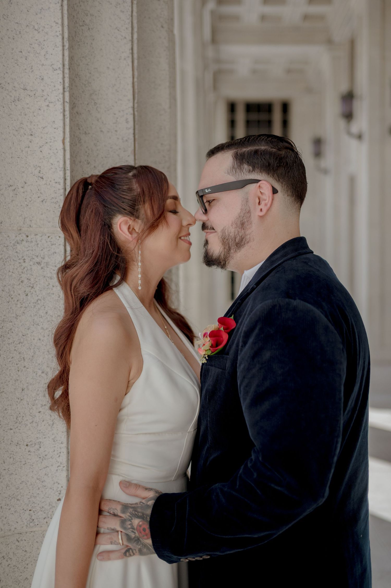 A romantic moment between newlyweds captured against a backdrop of stone columns.