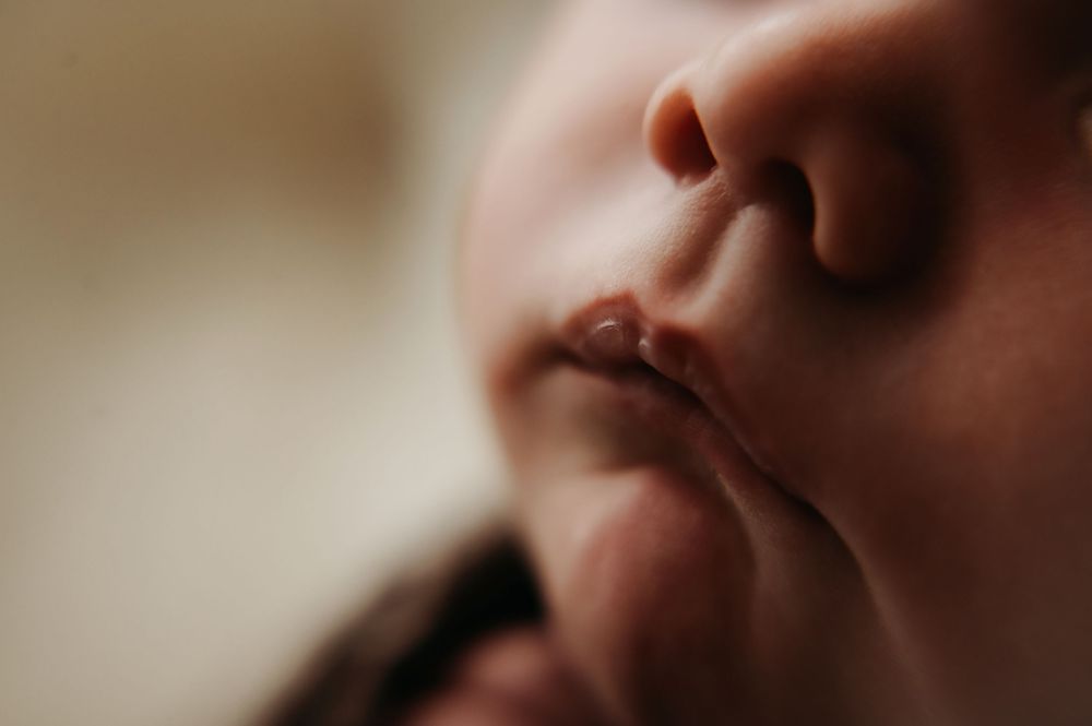 A close-up macro photograph shows a newborn lips and nose.