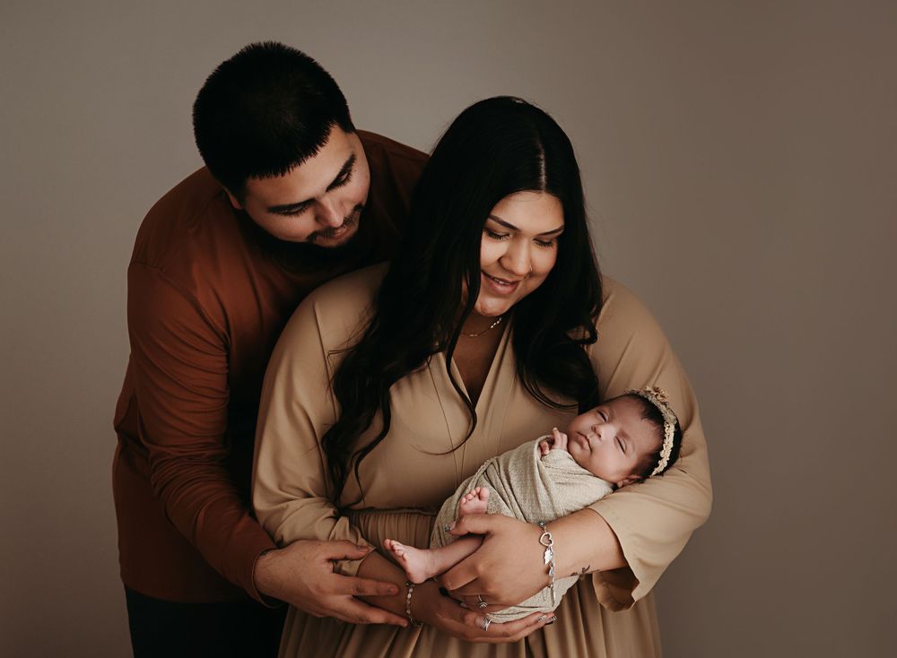 A series of tender family portraits showing parents with their newborn baby in a warm brown studio setting.