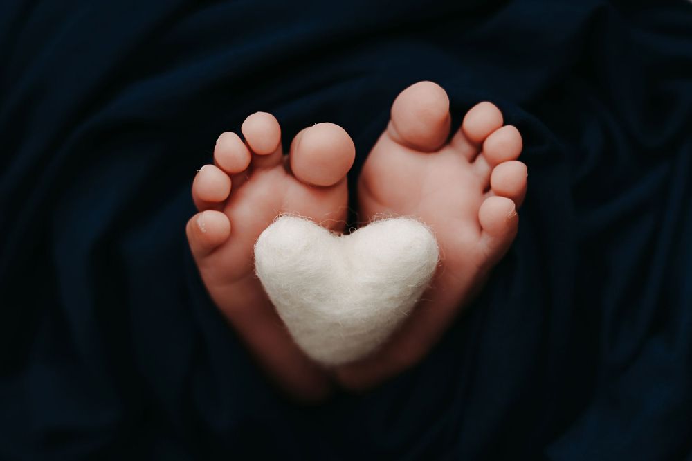 Detail image of newborn toes holding a small white heart.