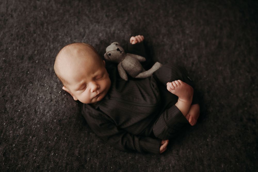 A series of black and white photos showing a sleeping baby in various peaceful poses on a dark textured background.