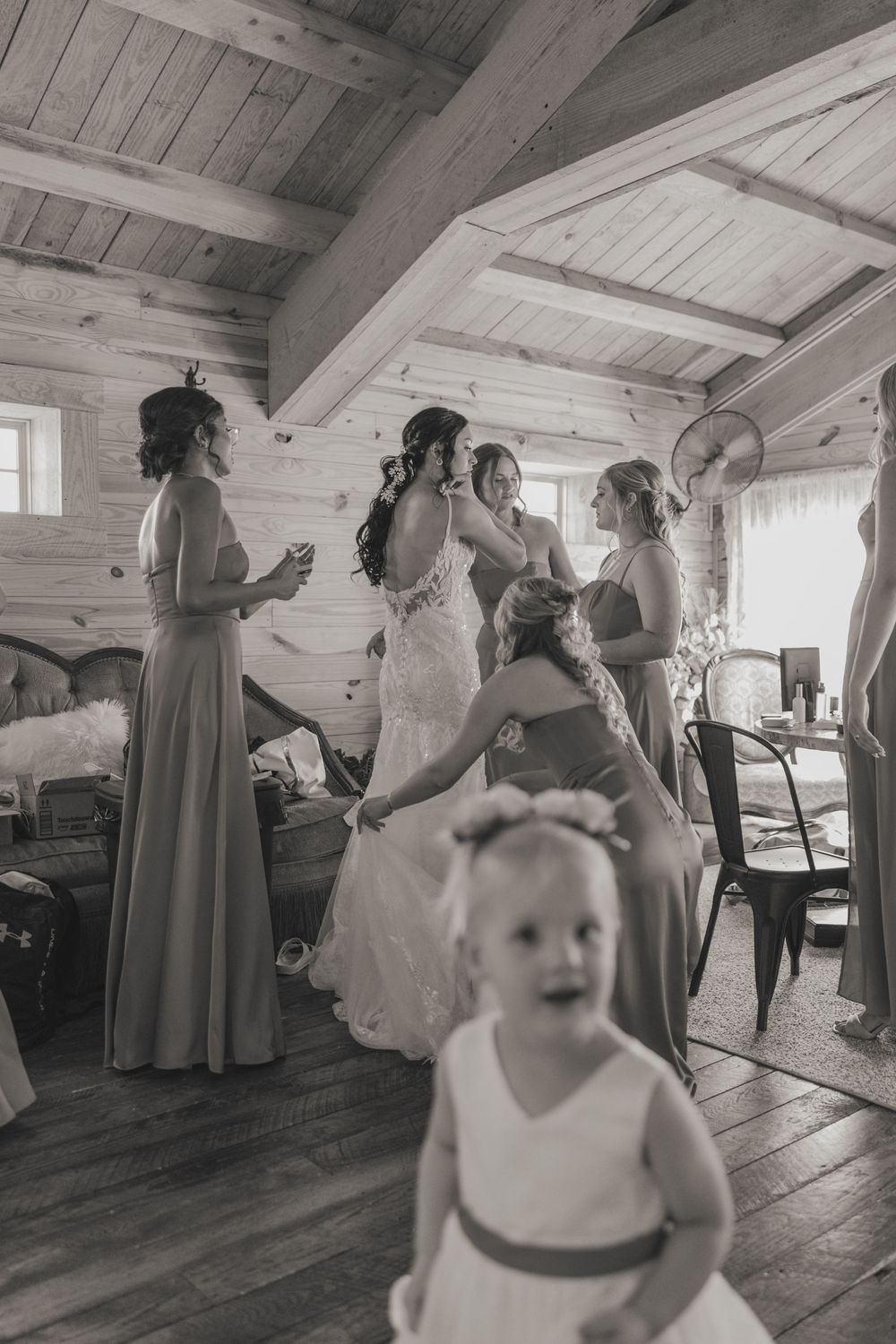 Black and white photos of wedding preparations in a rustic room with wooden walls and floors.