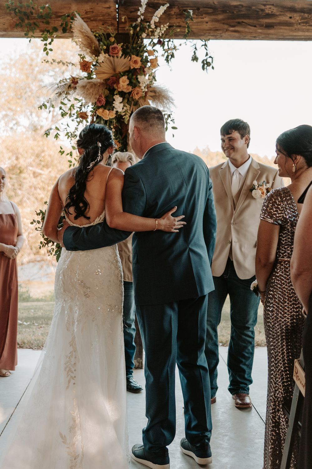 Wedding guests dancing and mingling on a dance floor with autumn decor and natural lighting.