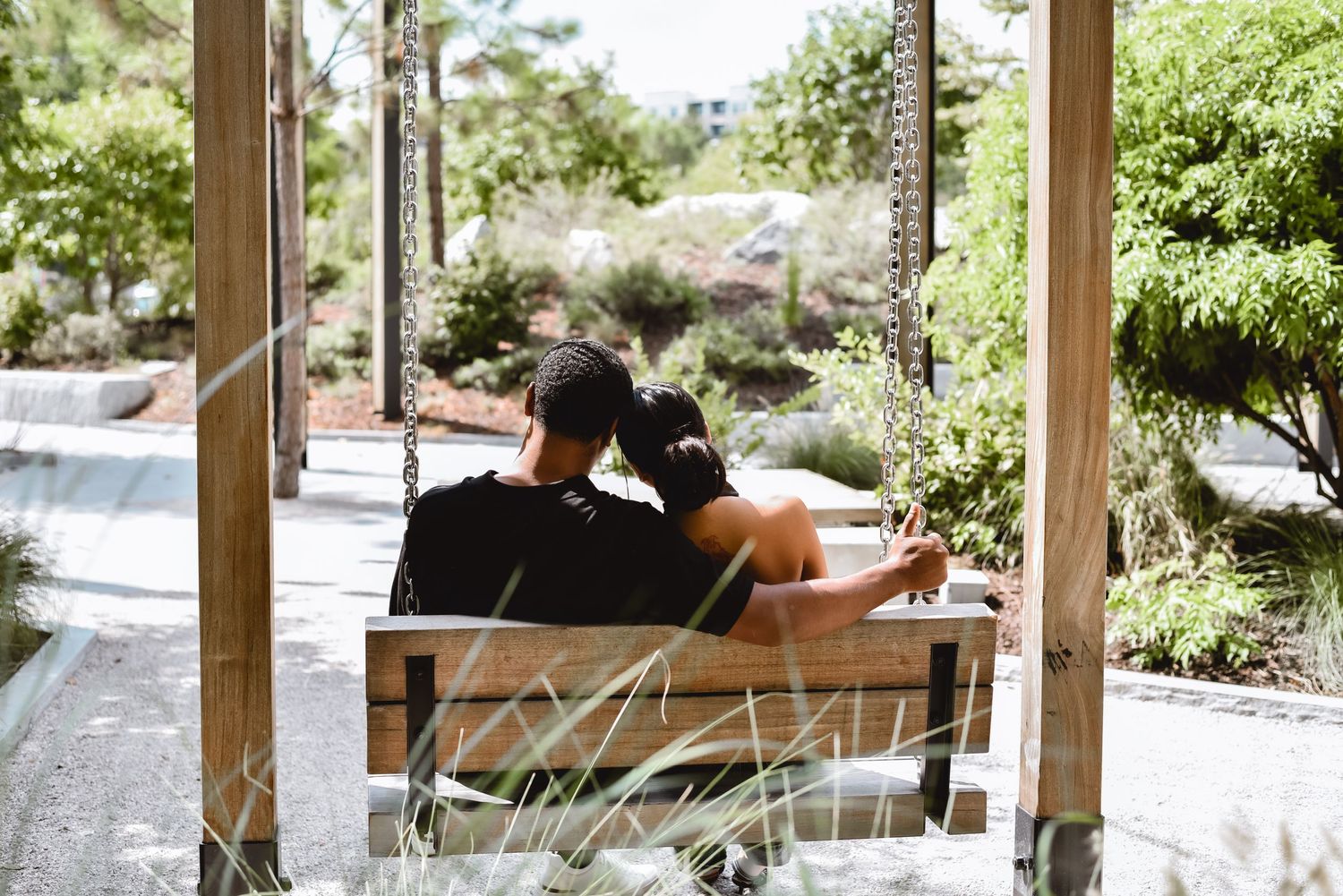People relaxing on a wooden bench in a serene garden setting with lush greenery and natural surroundings.