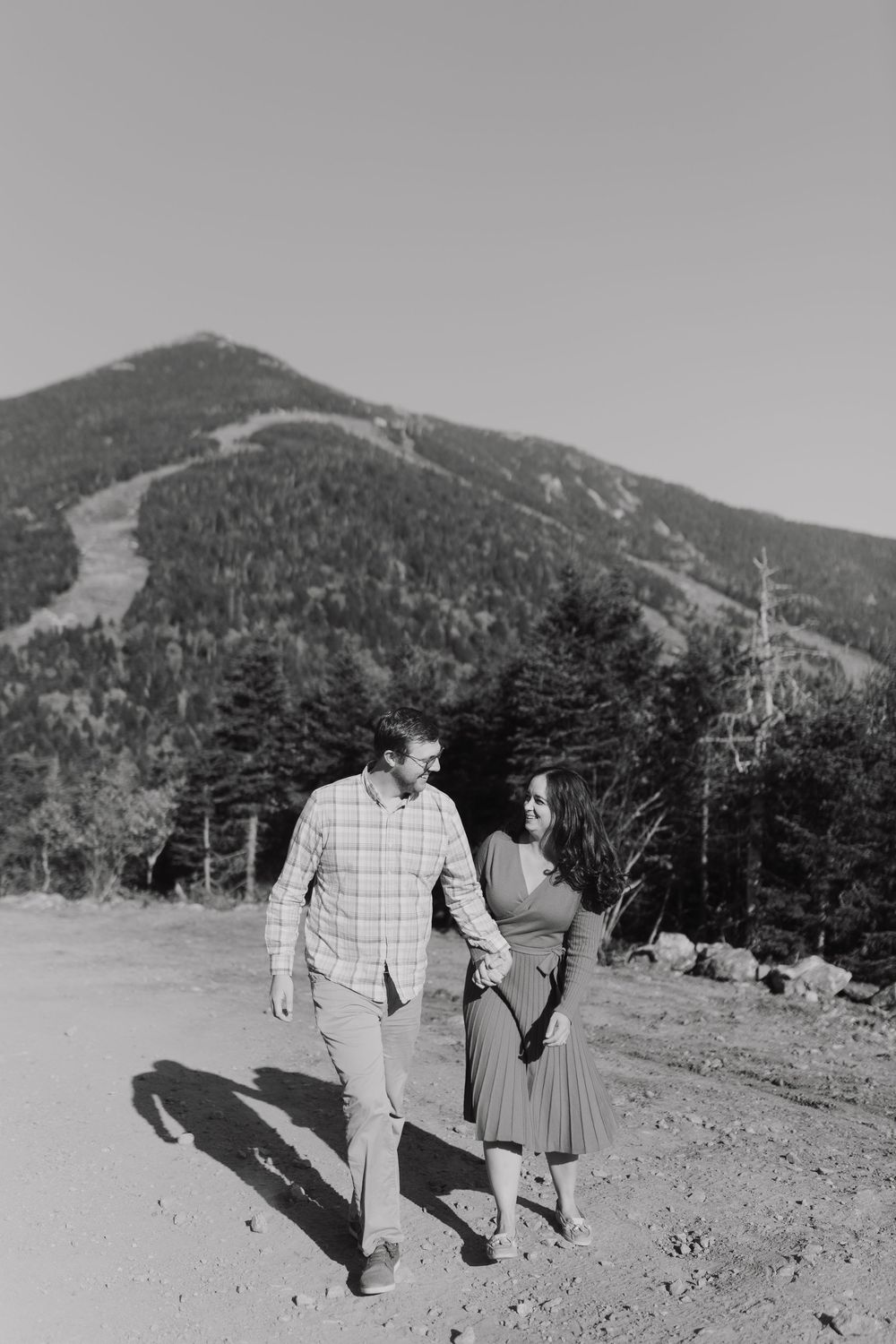 Black and white mountain engagement photos showing couple walking together on scenic trail.