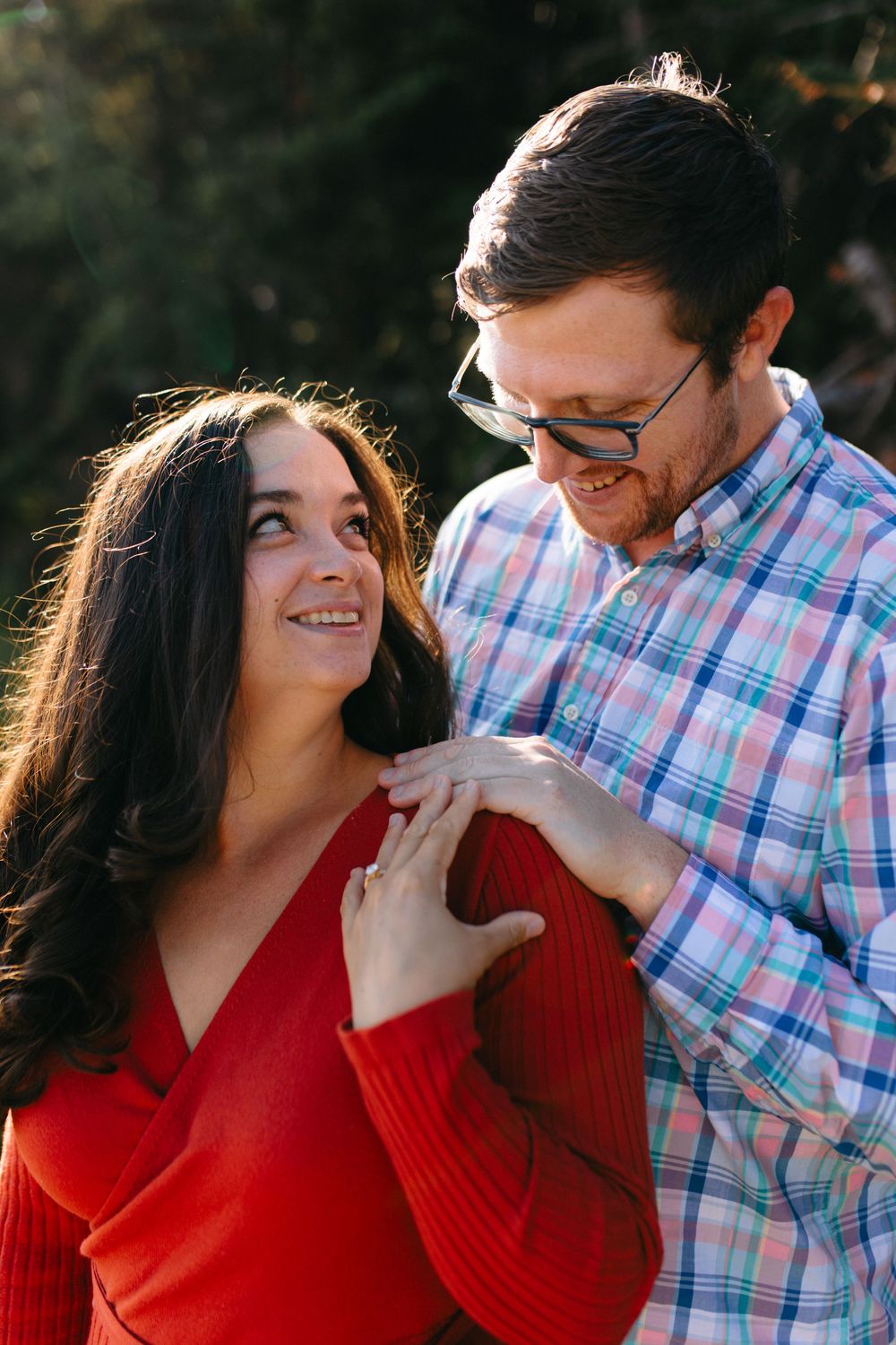 A couple shares intimate close-up moments while she wears a red sweater and he wears a plaid button-down.