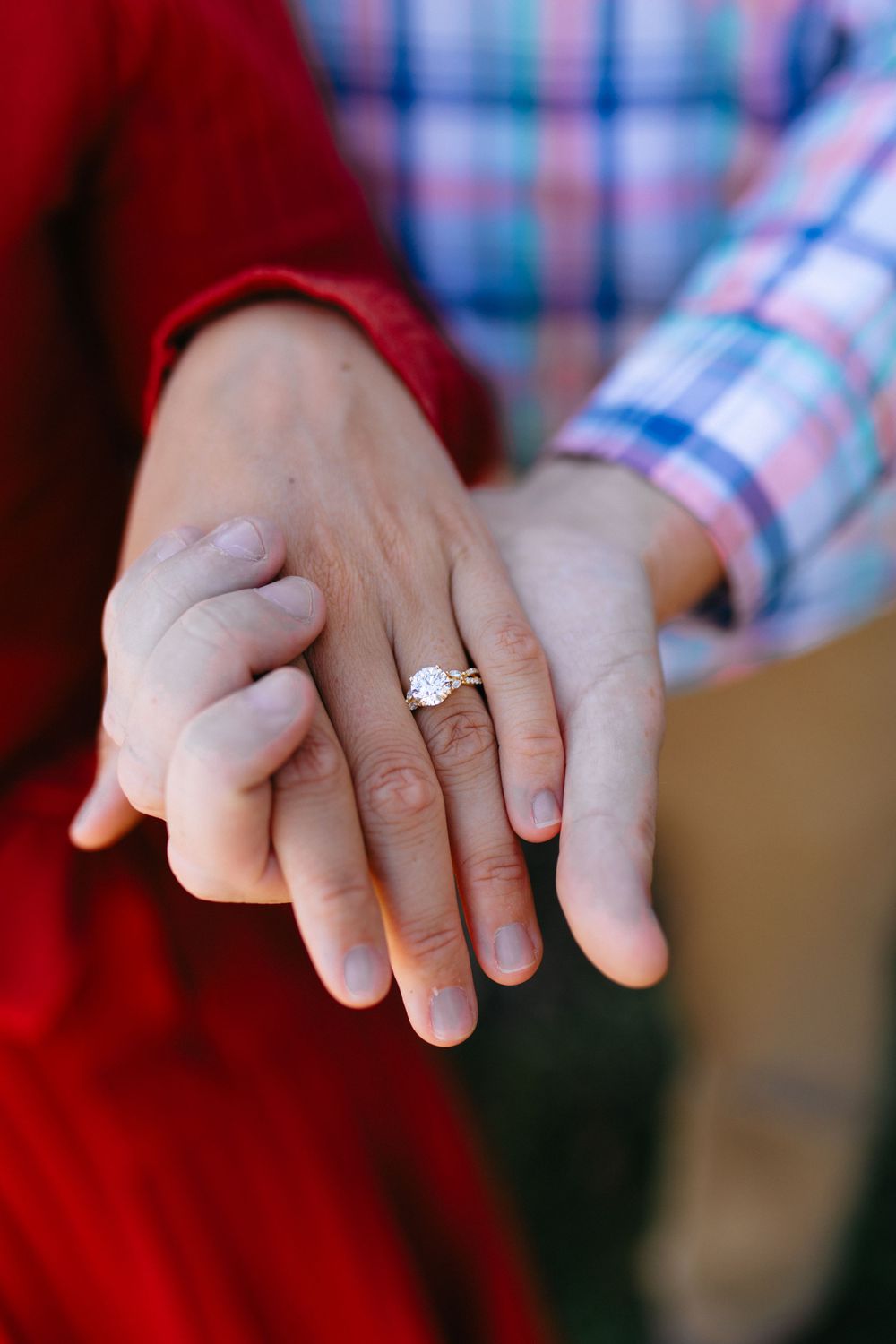 Close-up shots of hands holding and displaying an engagement ring against red and plaid clothing.