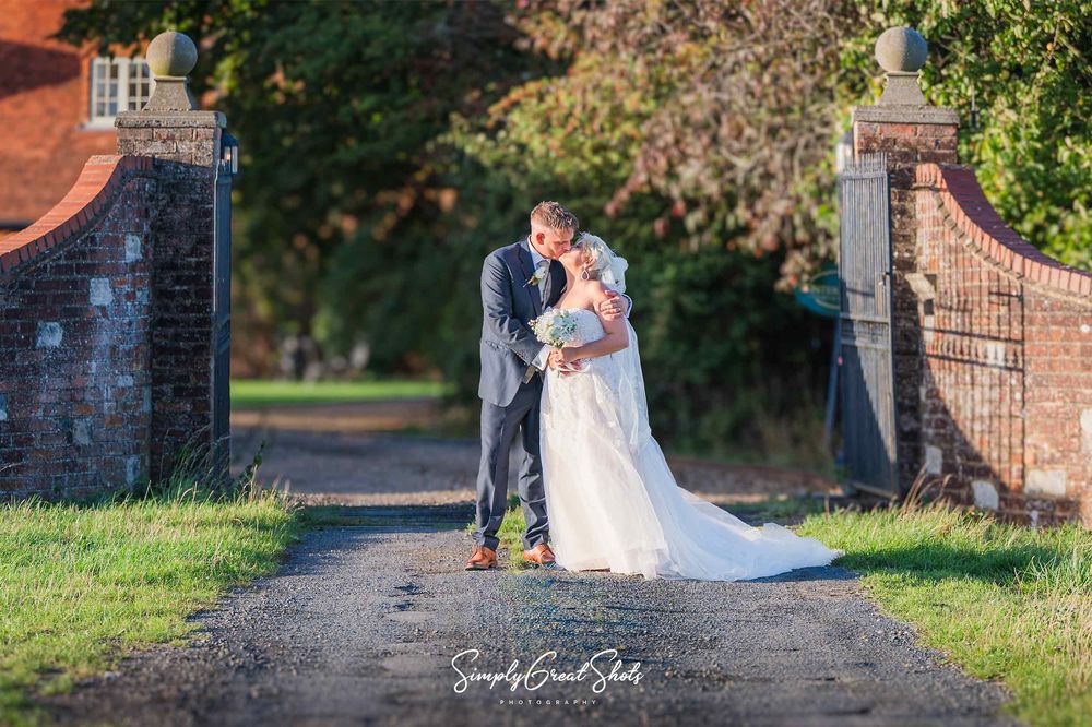 Buckinghamshire wedding photographer captures a bride & groom kissing in front of the entrance to the driveway to Winters Tale Country Barn