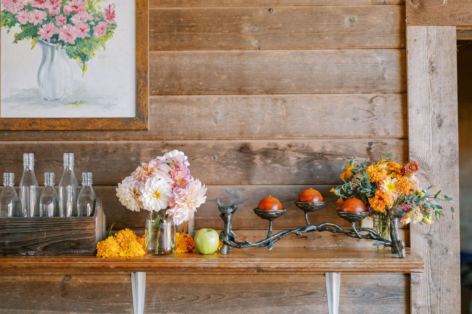 Rustic wooden shelves decorated with floral arrangements, bottles, and produce create an elegant farmhouse display.