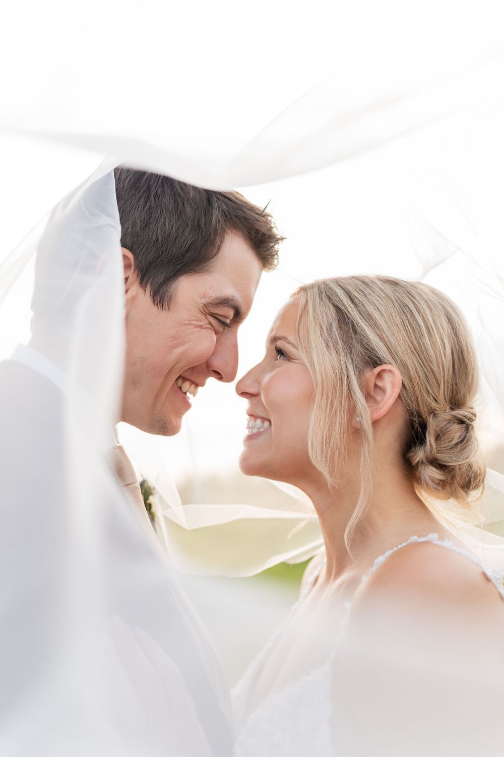 A romantic wedding couple shares tender moments under flowing white fabric in a series of intimate portraits.