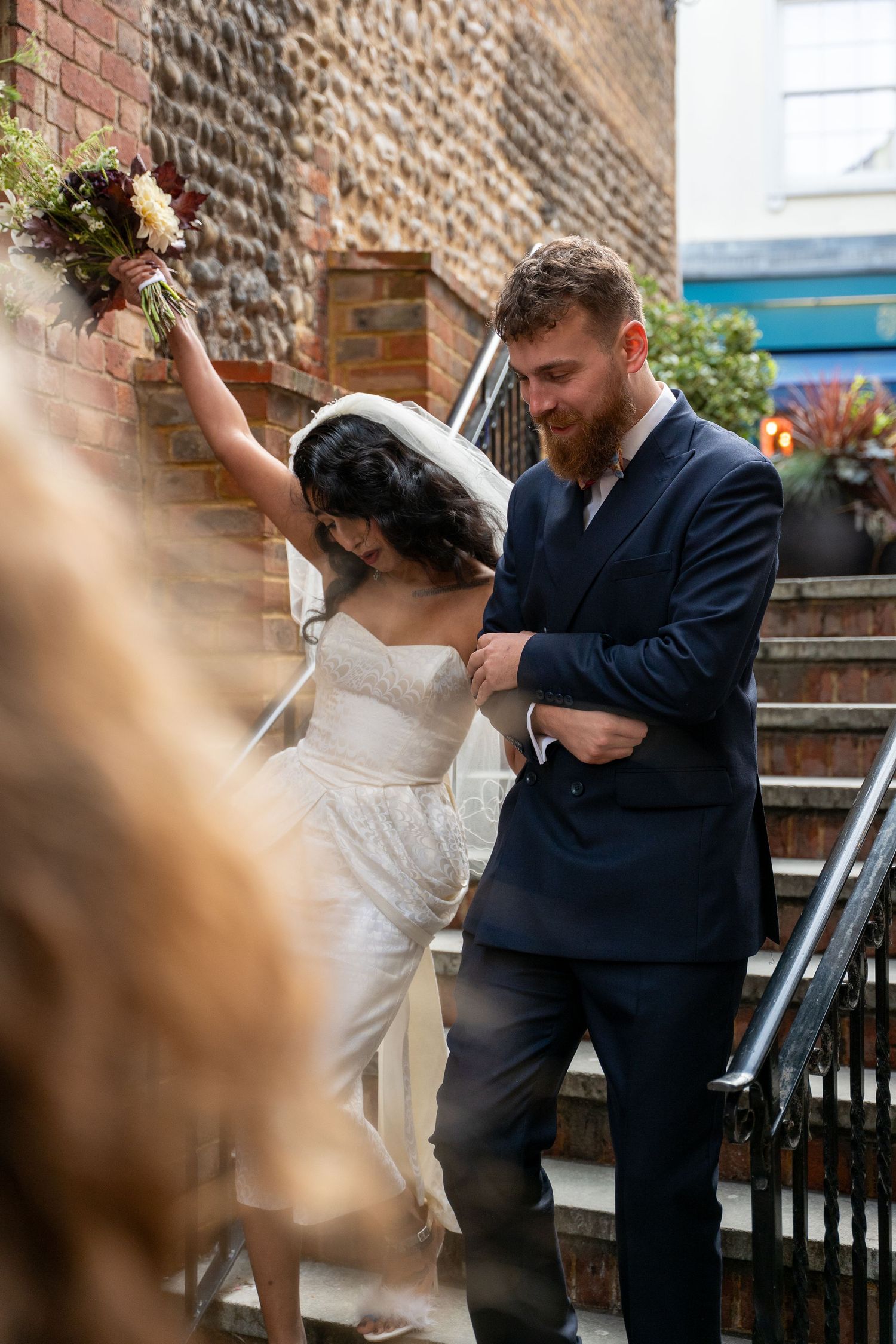 A couple dancing together in front of a brick wall, with the bride's dress swirling in motion.